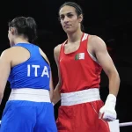 Algerian boxer Imane Khelif stands confidently in the ring next to her Italian opponent, wearing red gear with the Algerian flag emblem.